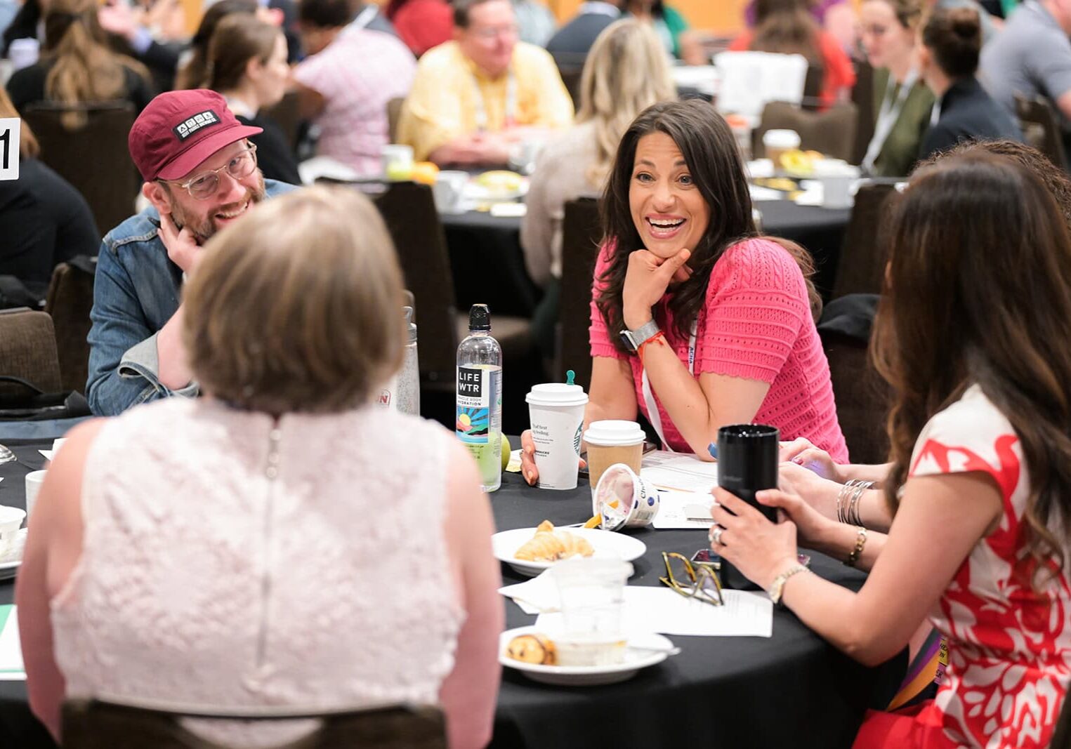 Excited conference attendees chatting at a table during a luncheon event