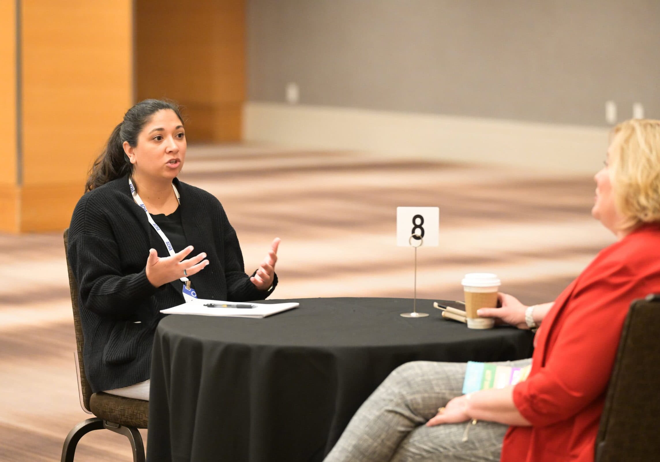 Two individuals at the ACHA 2024 Annual meeting seated at a table and having a discussion