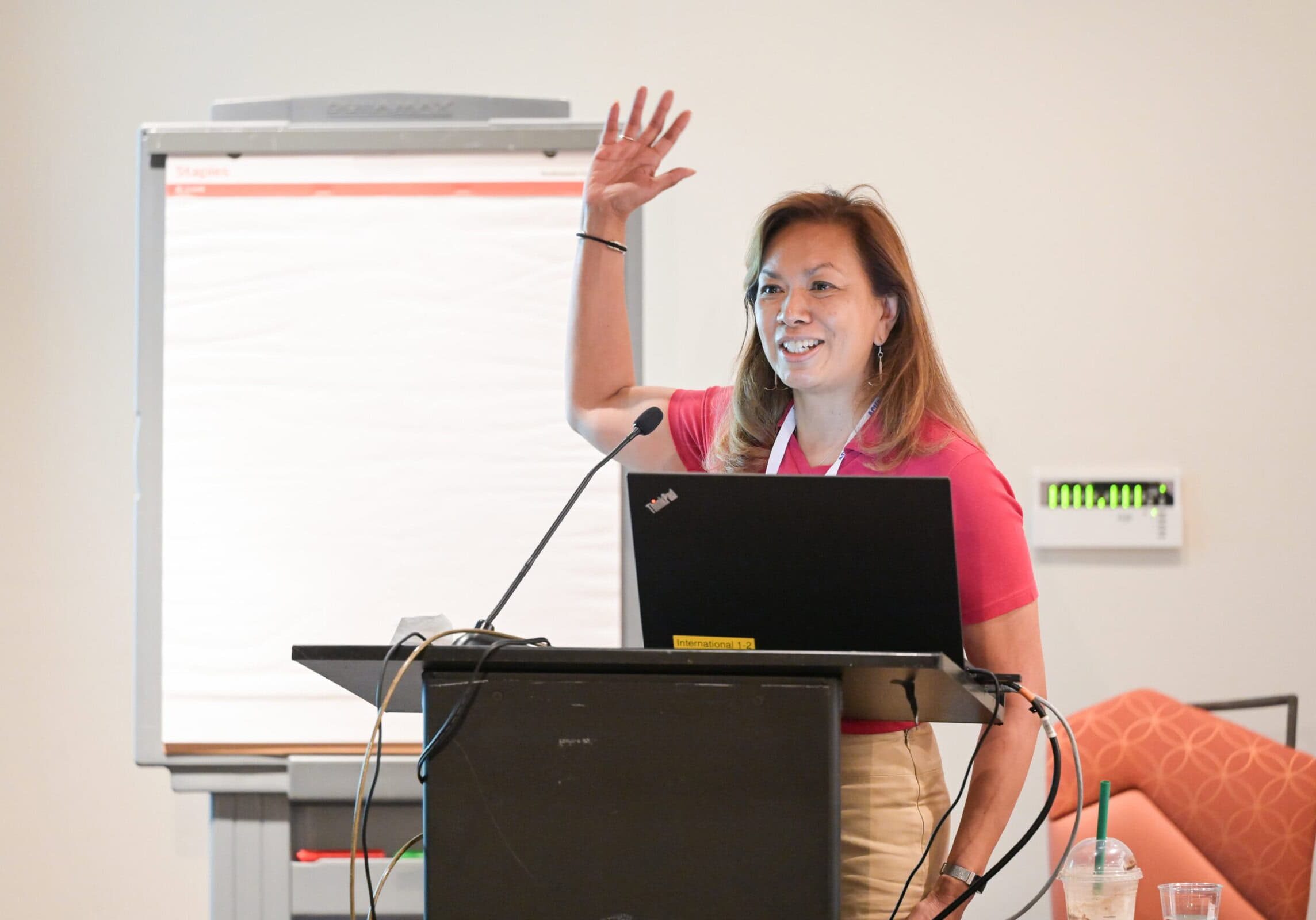 A speaker at the ACHA 2024 Annual Meeting standing at the podium and raising her hand