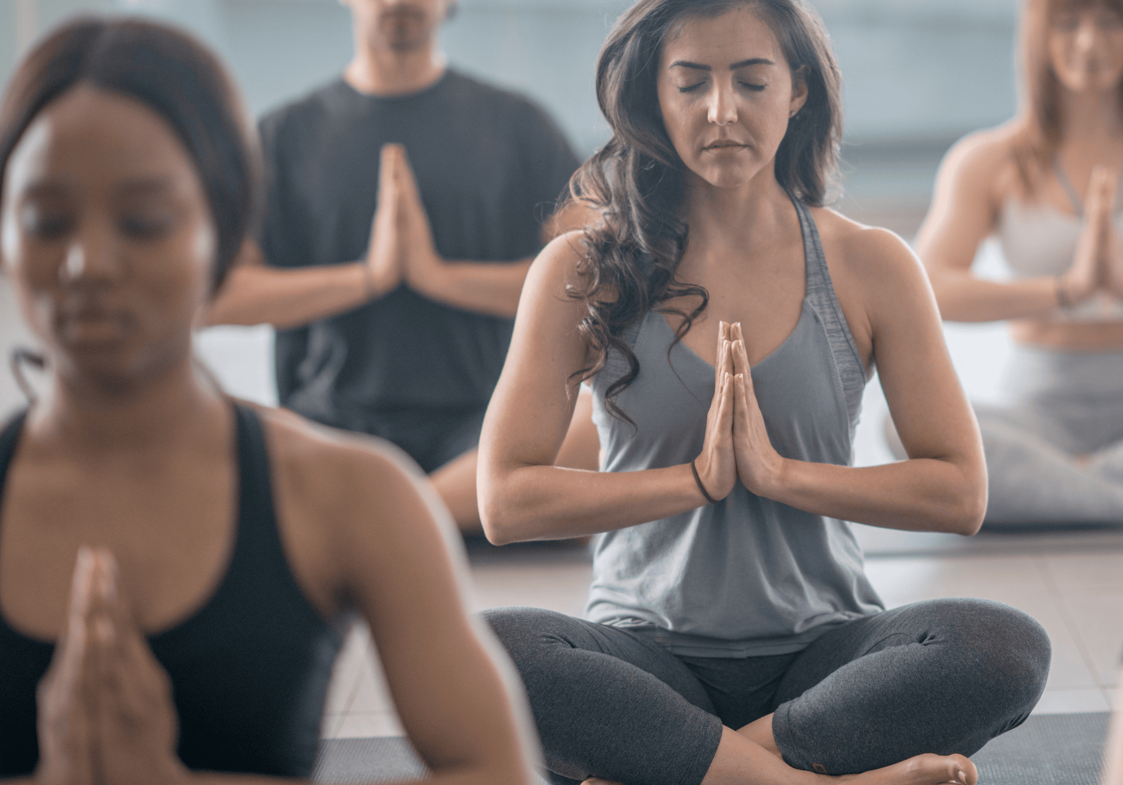 Photo of participants in a yoga class, seated doing a prayer pose.